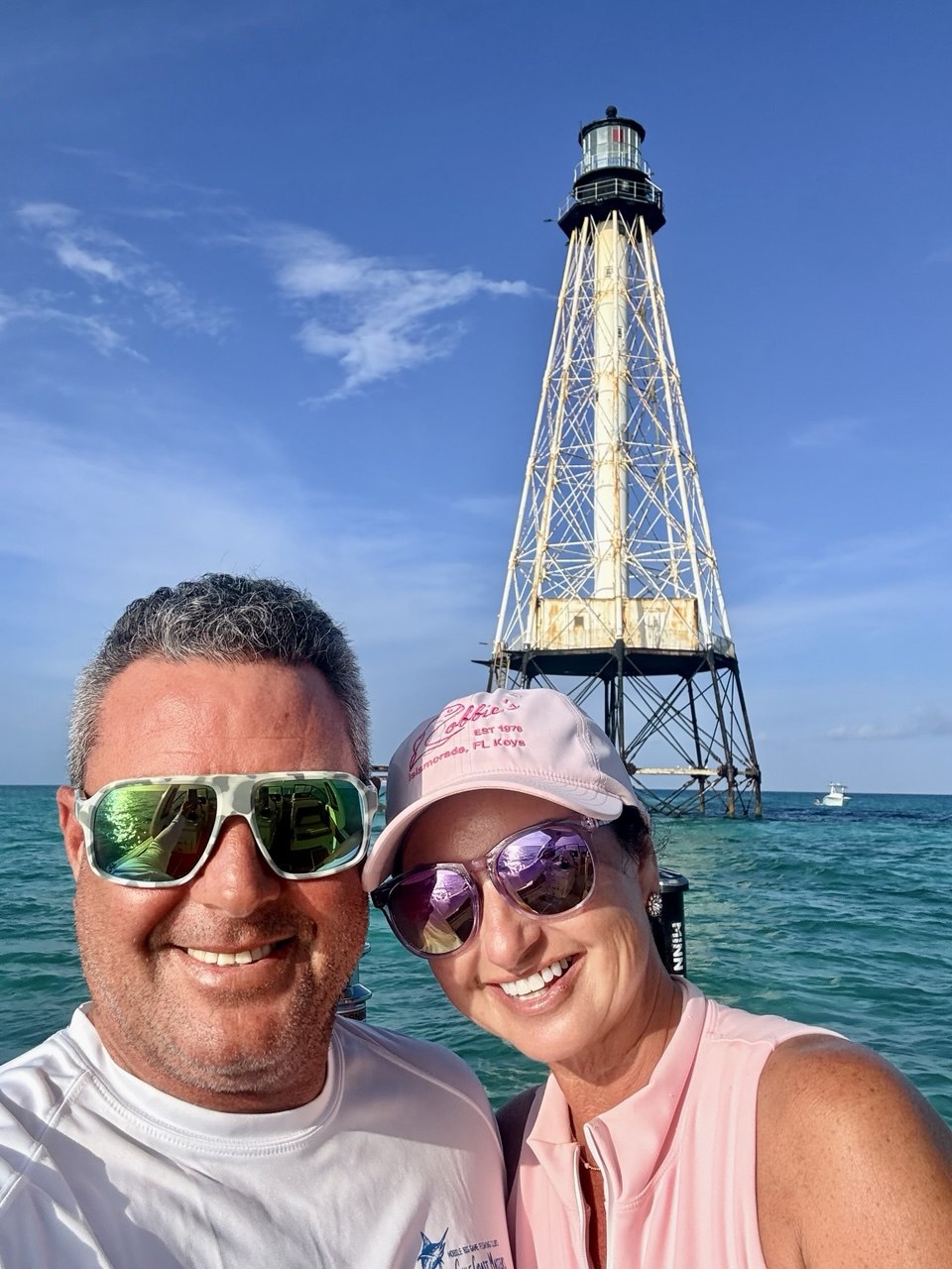 Couple smiling aboard a charter with Alligator Reef Lighthouse behind them