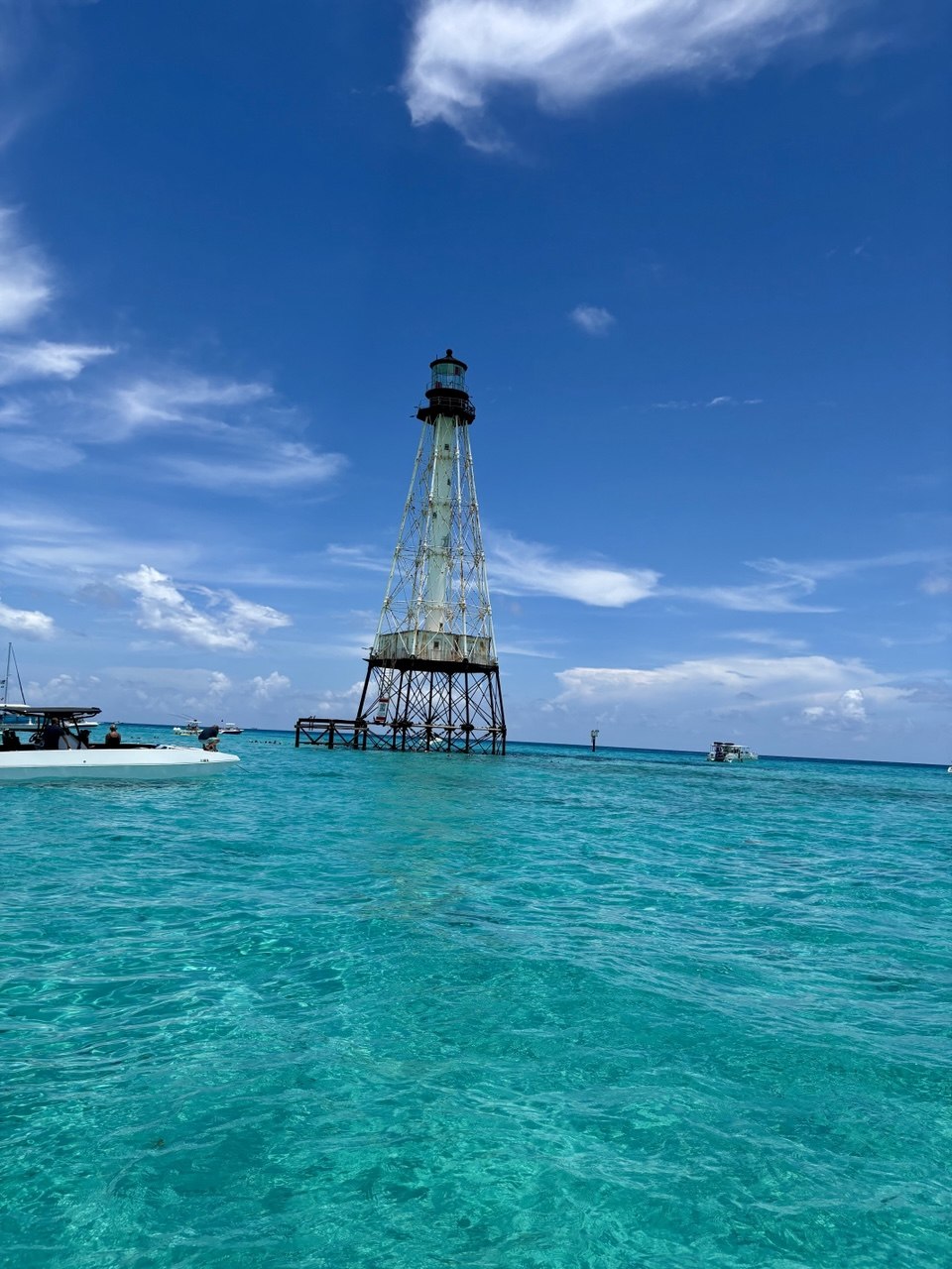 Full Alligator Reef Lighthouse surrounded by turquoise water beneath a blue Florida Keys sky
